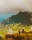一对夫妇欣赏着天空中令人惊叹的彩虹和山地景观