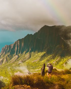 一对夫妇欣赏着天空中令人惊叹的彩虹和山地景观