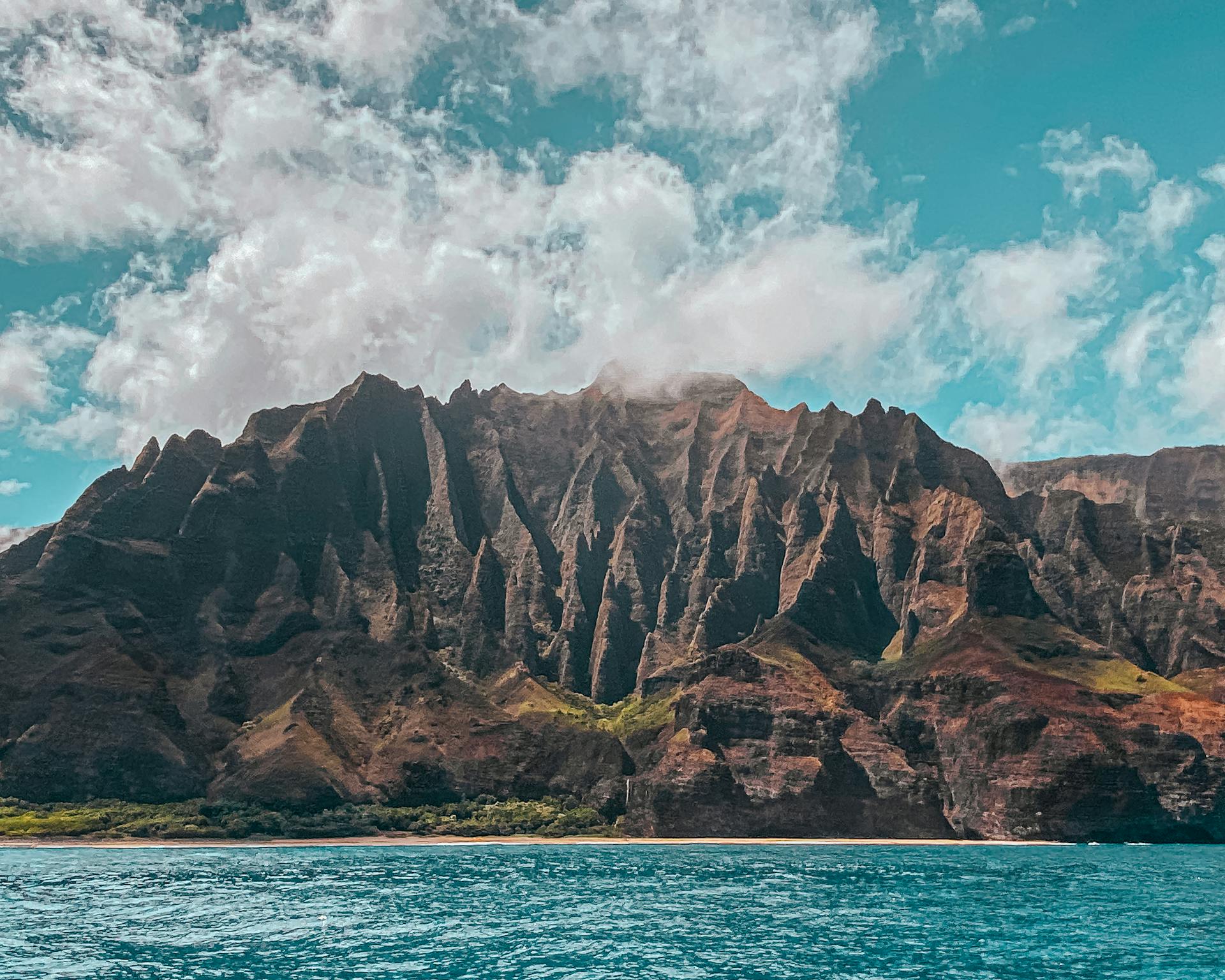 Stunning view of the Na Pali Coast, showcasing rugged cliffs and vibrant blue sea under a bright sky.