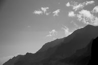 Grayscale Photo of Mountains Under Cloudy Sky