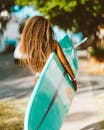 Back View of Brown Haired Woman Walking with a Turquoise Surfboard