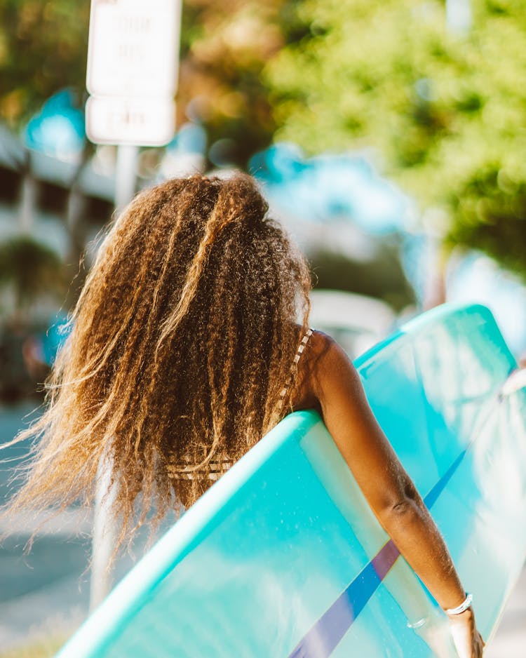 Woman Holding Surfboard And Walking