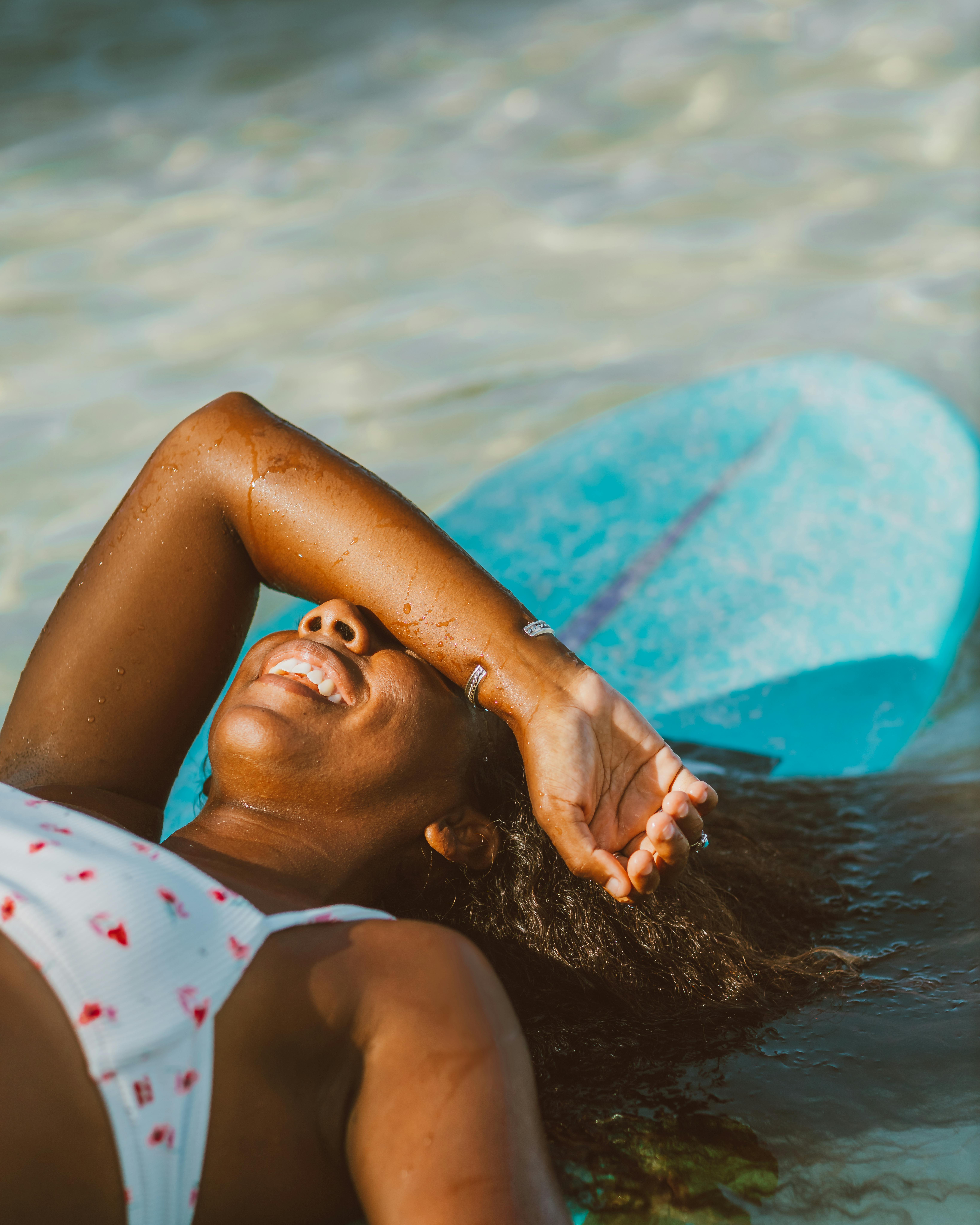 妇女放松愉快地在海滩上与冲浪板在一个阳光明媚的夏日
