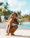 Woman in White Bikini Sitting on Blue Surfboard on Beach