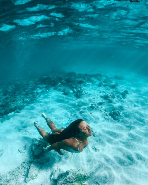 Free A woman enjoys peaceful freediving underwater in clear blue ocean waters. Stock Photo