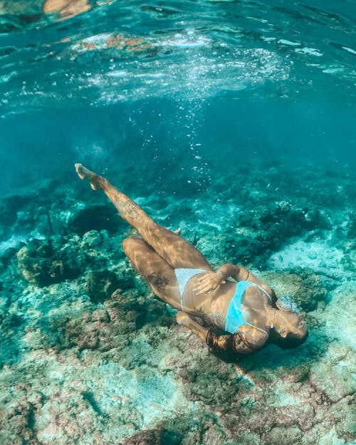 Free A Woman Lying Near the Coral Reef Under Water Stock Photo