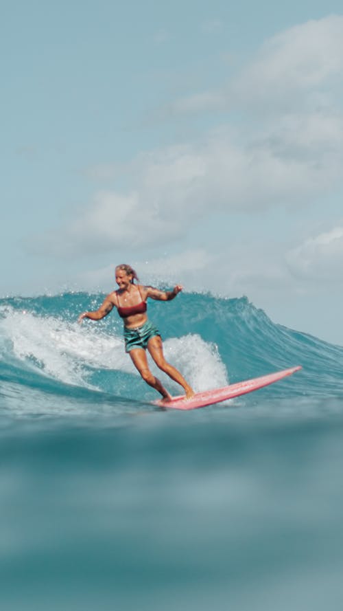 Woman Wearing Swimsuit and Board Shorts Riding Surfboard