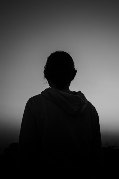 Free A silhouetted person stands against a twilight sky, evoking a sense of solitude and reflection. Stock Photo