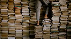 Person Standing on Stacks of Books