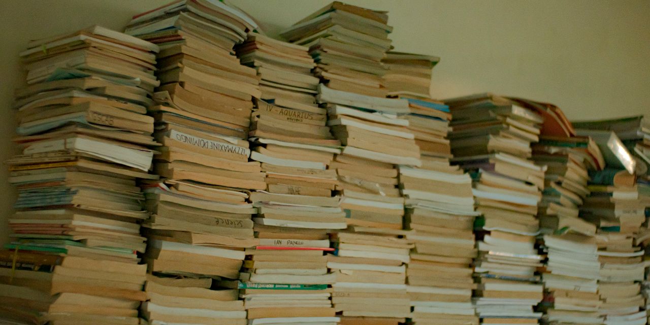 A large collection of stacked, vintage books in an indoor library setting, conveying wisdom and knowledge.