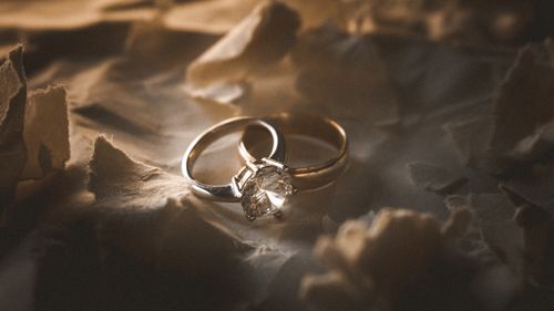 Free Close-up shot of elegant diamond and gold rings on textured paper background. Stock Photo