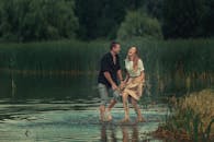 一对快乐的夫妇在宁静的湖畔嬉戏，四周环绕着郁郁葱葱的绿植