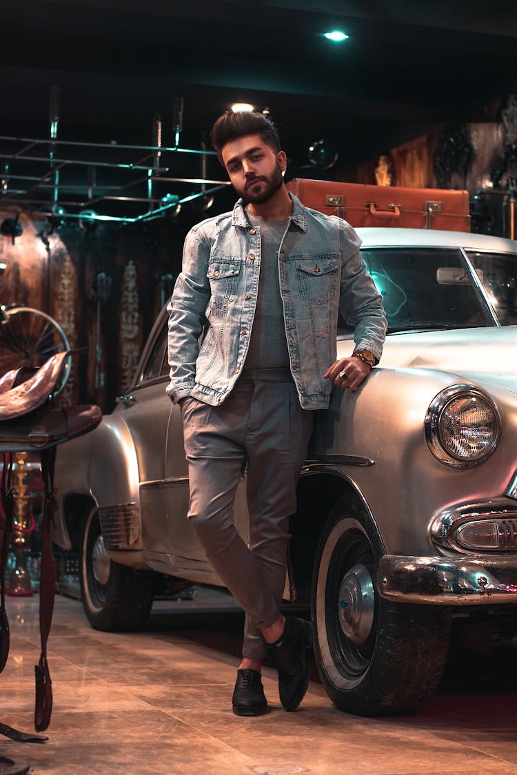 A Young Man In A Denim Jacket Standing By A Vintage Car