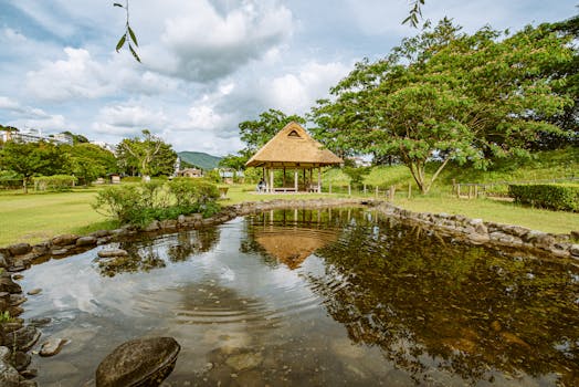 Idyllic garden scene featuring a tranquil pond and a traditional thatched roof pavilion.
