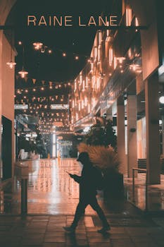 A silhouette of a person walking at night beneath vibrant street lights in Raine Lane, Perth, Australia.