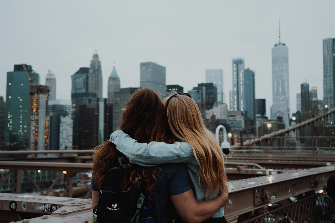 Woman in Blue Shirt and Black Backpack Standing on Top of Building