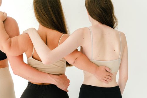 Free Three women with long hair embrace, showcasing unity and friendship in a minimalist setting. Stock Photo