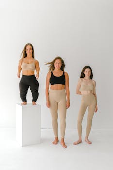Three women of diverse heights embracing body positivity in a bright studio setting.