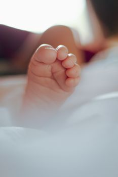 柔焦特写中，新生婴儿的脚放在白色床上，捕捉到纯真与温暖