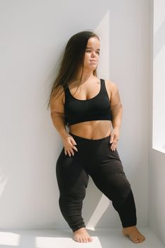 一位自信的侏儒症女性身着黑色运动服，拥抱身体积极性和赋权
