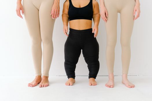 三位身着运动服的女性站在白色背景下，展现身体的活力