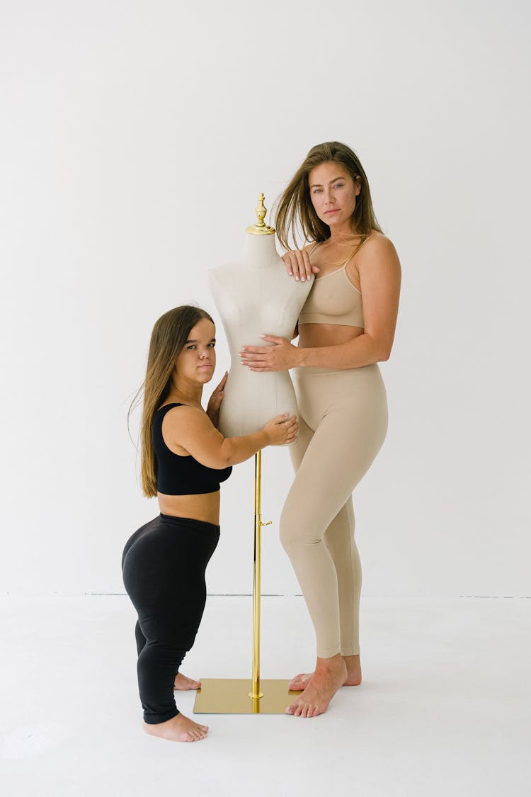 Women In Activewear Standing Beside A Mannequin While Posing At The Camera