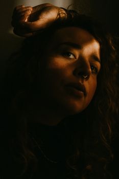 一位卷发、戴鼻环的女人的戏剧性阴影肖像