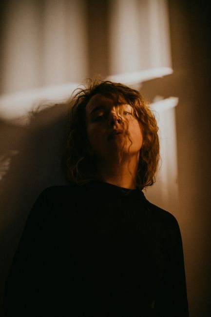 Artistic portrait of a woman in shadows, creating a mysterious atmosphere indoors.