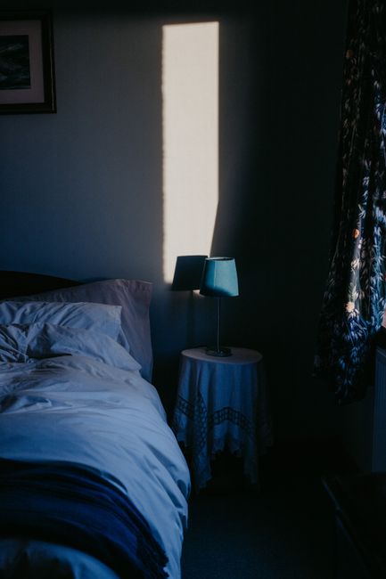 Sunlight casts dramatic shadows in a serene Scottish bedroom setting, emphasizing tranquil elegance.