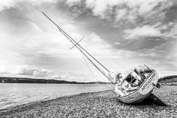 Grayscale Photo Of A Tilted Sailboat On Shore