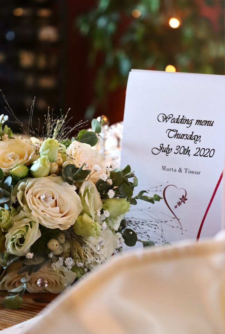 Close-up Of A Flower Arrangement And A Wedding Menu Card 