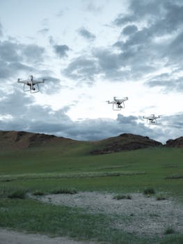 Drones soar over a grassy field with a cloudy sky backdrop, capturing the essence of modern aviation and nature.