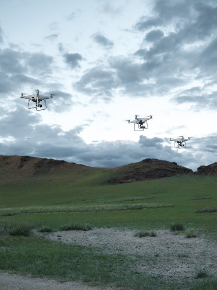 Drones Flying Over Grass Field