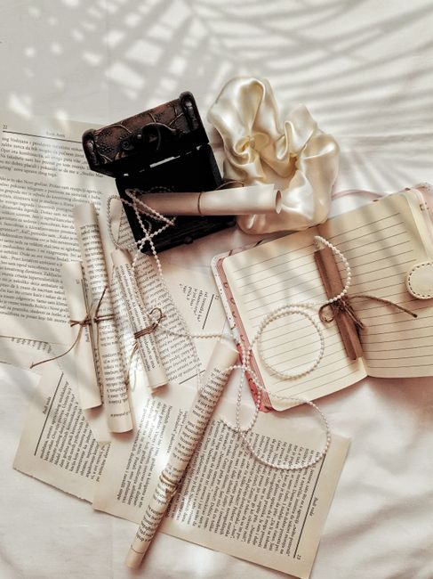 Aesthetic flat lay of vintage rolls, journals, and pearls with shadows on a white background.