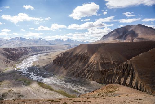 Free Breathtaking aerial view of a rugged mountainous valley with a winding river and clear skies. Stock Photo