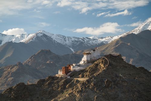 Free A stunning view of an ancient Tibetan monastery perched on a mountain surrounded by the Himalayas under a clear blue sky. Stock Photo
