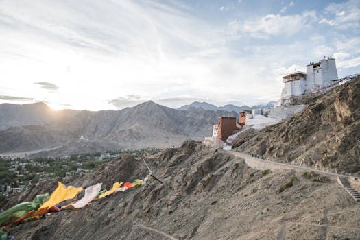 Aerial view of Namgyal Tsemo Monastery perched on rocky hills in Leh, Ladakh, with a sunset backdrop.