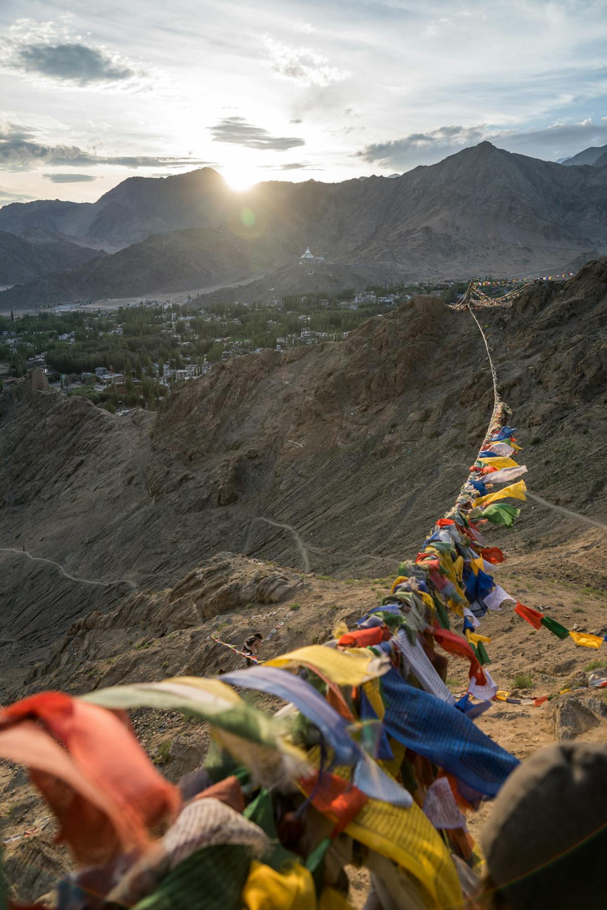Prayer flags hanging across a mountain pass with Himalayan peaks in the background