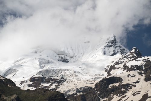 Free A breathtaking view of a snow-capped mountain peak partially covered by clouds, embodying winter's beauty. Stock Photo