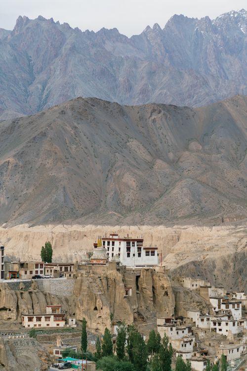 Free Explore the serene beauty of an ancient village nestled in a rocky desert landscape with towering mountains. Stock Photo