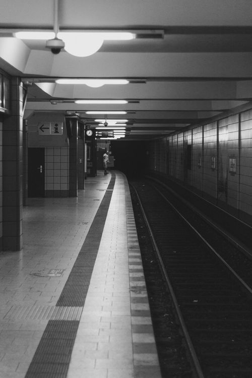 Free Grayscale image of a deserted Berlin subway station platform with tracks leading into darkness. Stock Photo