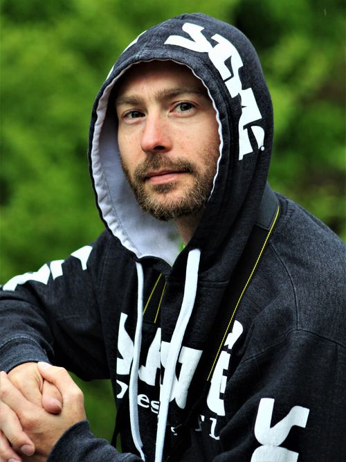 Free Man in dark hoodie outdoors with facial hair, looking relaxed and casual. Stock Photo