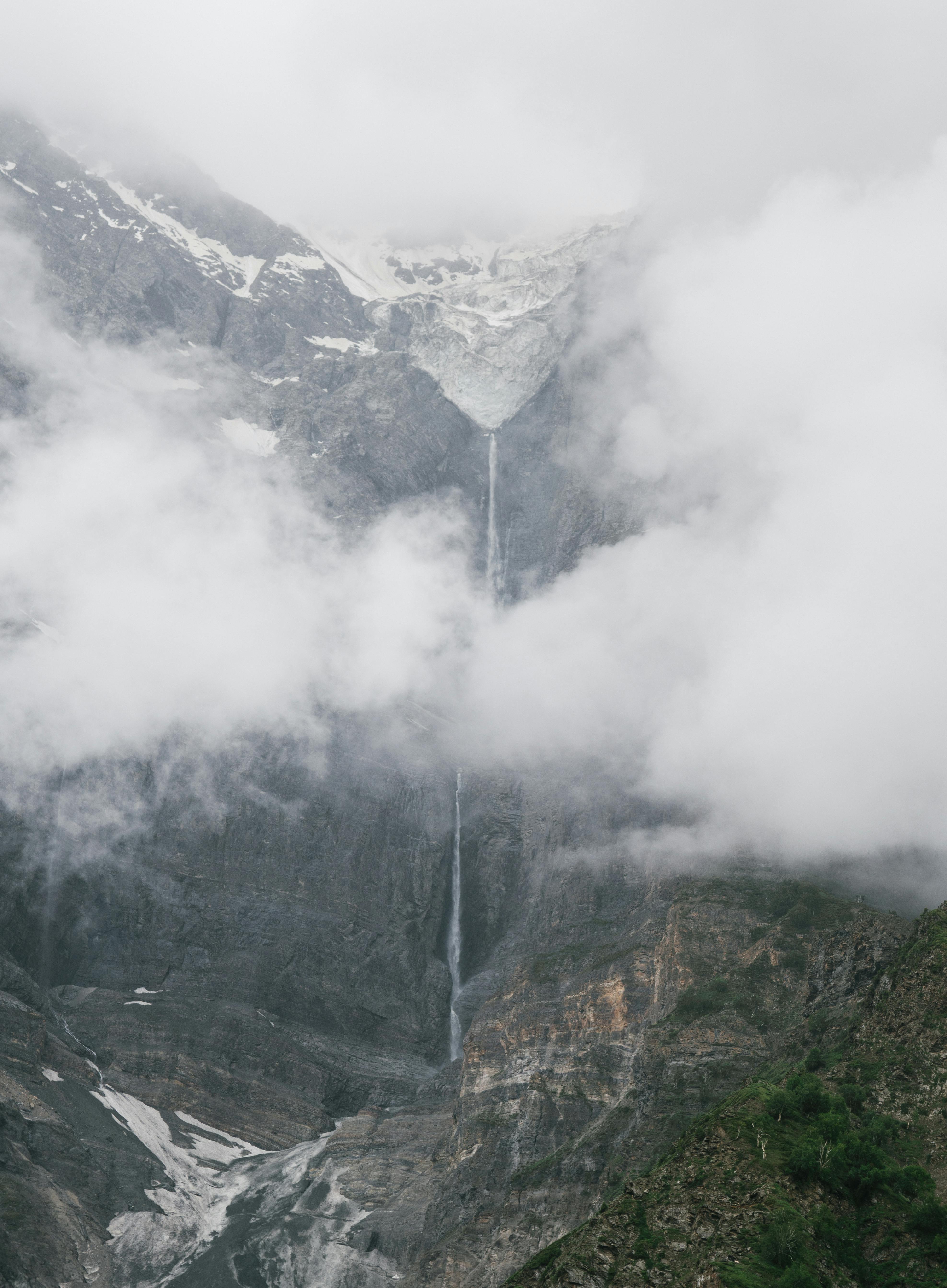 从空中俯瞰，瀑布流过雾气缭绕、白雪皑皑的山脉，令人惊叹地展示了大自然的壮丽之美