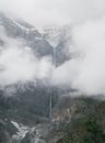 从空中俯瞰，瀑布流过雾气缭绕、白雪皑皑的山脉，令人惊叹地展示了大自然的壮丽之美