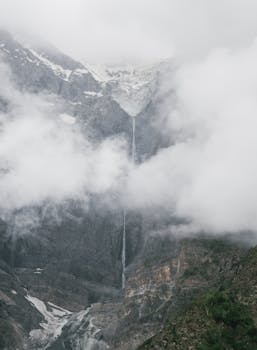 从空中俯瞰，瀑布流过雾气缭绕、白雪皑皑的山脉，令人惊叹地展示了大自然的壮丽之美