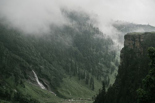 Free A scenic misty mountain view with lush forests and a waterfall, perfect for nature lovers. Stock Photo