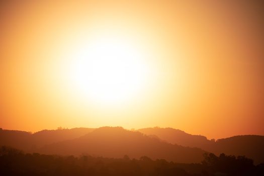 Silhouette of mountains under a bright sunset with a golden sky.