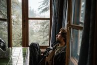 Man in Black Jacket Sitting on Chair Beside Window