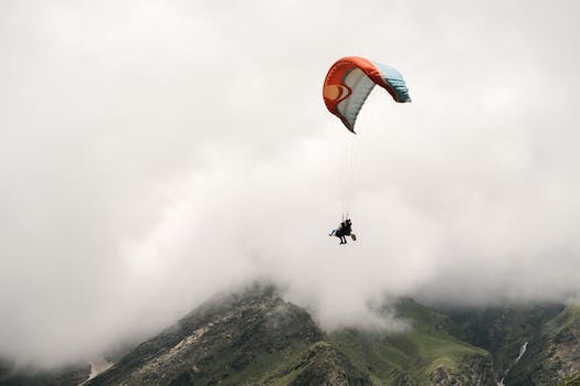 A paraglider soars above mist-covered mountains, capturing the essence of freedom.