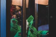 A woman in a green jacket uses a payphone in Los Angeles, CA.